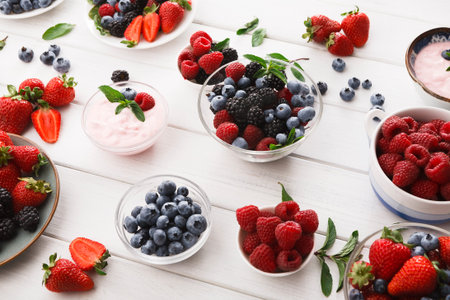 Fresh Fruit Collection Arranged on a White Table With Yogurt Cups and Mint Leaves