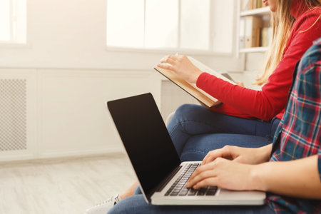 People Engaged in Reading and Typing at a Shared Workspace in a Bright Room in the Afternoon