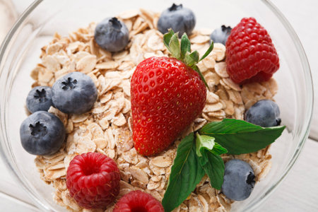 Healthy Breakfast Bowl With Oats, Berries, and Mint Leaves on Wooden Table