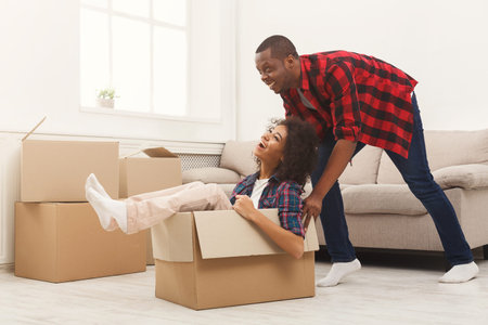 Couple Enjoys Playful Moment in Living Room With Moving Boxes and Laughter