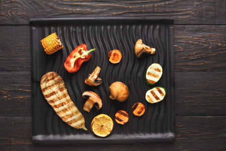 Colorful Food Collage on Black Plate With Grilled Vegetables and Meat in a Variety of Shapesの写真素材