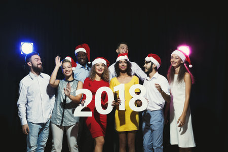 Group of Friends Celebrating New Years Eve With Hats and a Big Sign in 2018