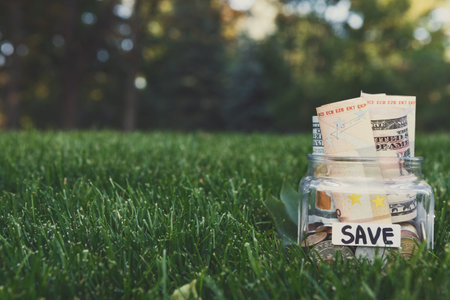 Money Saved in a Jar Placed on Green Grass in a Garden During Daylight