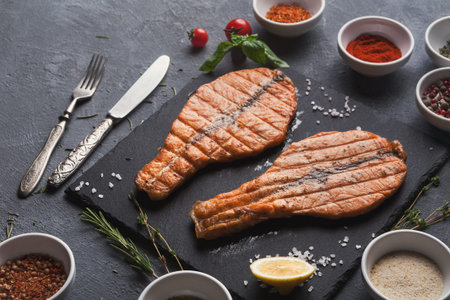 Freshly Grilled Salmon With Spices and Herbs on a Black Slate Serving Board in the Kitchenの写真素材