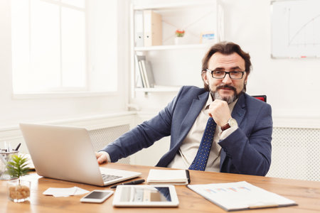 Businessman Working in an Office During Daylight Hours With Laptop and Documents on the Desk