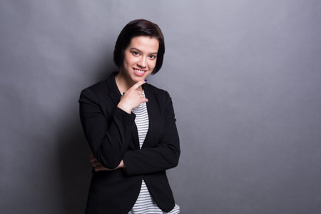 Woman Posing Confidently With a Thoughtful Expression Against a Gray Background