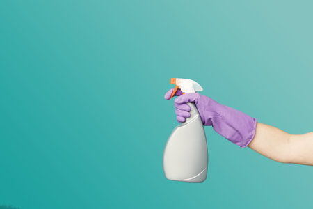 Hand Holds Cleaning Spray Bottle in a Bright, Simple Indoor Space for Use