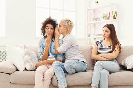 Friends Share Secrets on a Couch While One Looks Unhappy in a Bright Room