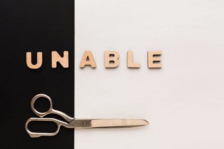 Letters Spelling Unable on a Black and White Surface With Scissors Nearbyの写真素材