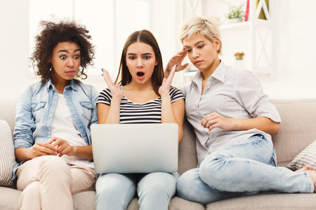 Group of Friends Reacting to Something Surprising on a Laptop in a Cozy Living Room Setting