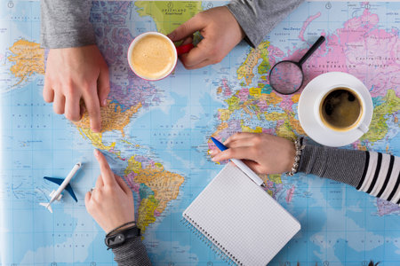 Group Plans Travel on World Map With Coffee Cups and Notebook in the Afternoon