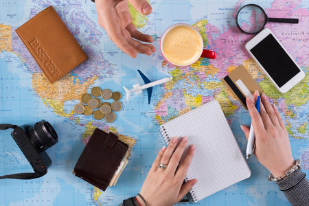 Planning a Trip With a Map, Travel Items, and Discussion Over Coffee and Notes