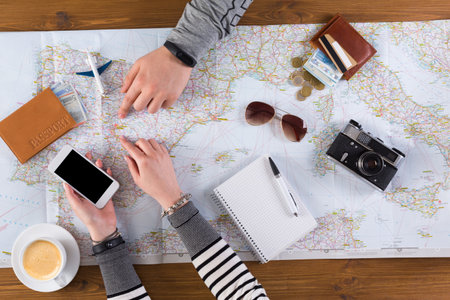 Planning a Travel Route With a Map and Smartphone at a Wooden Table
