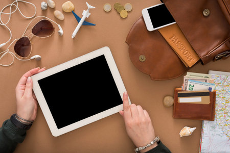 Preparing for Travel With a Tablet, Money, and Travel Items on a Table