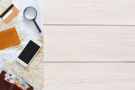 Items on a Table Ready for Travel Preparation, Featuring a Map, Phone, and Passportの写真素材
