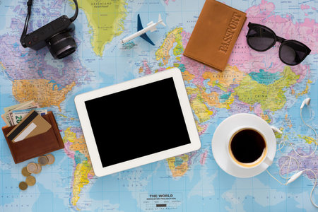 Exploring Travel Essentials on a Map With Coffee, Camera, and Tablet in a Workspace Setup