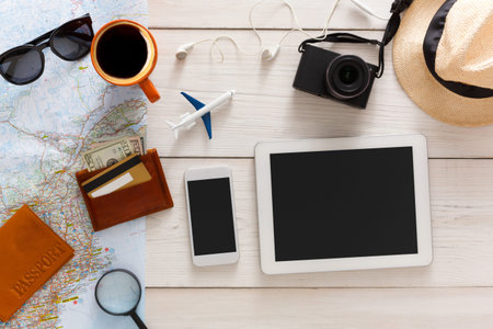 Preparing for Travel With a Map, Devices, and Other Essentials on a Wooden Table