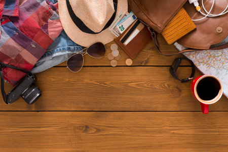 Preparing for a Trip With Travel Essentials, Clothes, and Accessories on a Wooden Table