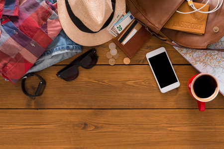 Travel Preparation Includes Items Like Clothes, Currency, and a Smartphone on a Wooden Table