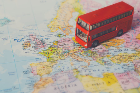 Red Toy Bus on a Detailed Map of Europe Highlighting Various Countries and Cities