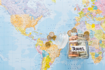 Saving Money for Travel With a Jar and Coins on a World Map in Daylight