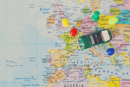 Exploring Europe With a Green Toy Car on a Map With Colorful Pushpins Marking Locations
