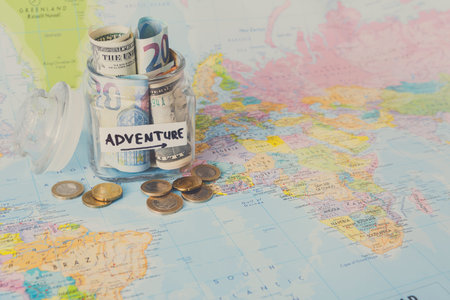 Money Jar Placed on a World Map With Rolled Bills and Coins for Future Travels and Adventures
