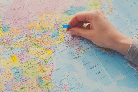 Hand Placing a Marker on a Map of Asia While Planning a Trip Across Countries and Citiesの写真素材