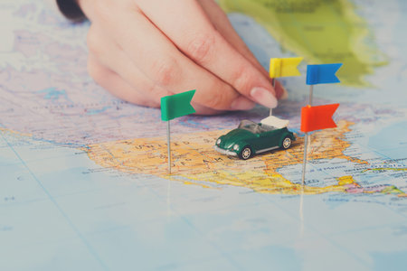 Planning a Road Trip Using a Map and a Toy Car With Color Flags on the Table