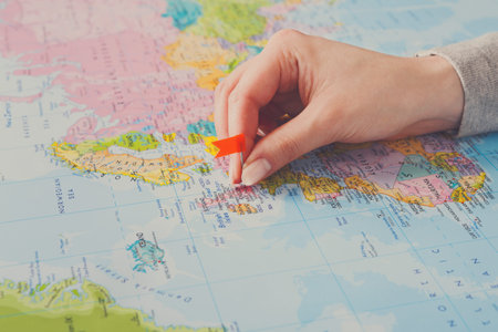 Marking Specific Locations on a World Map With a Red Push Pin in an Indoor Setting