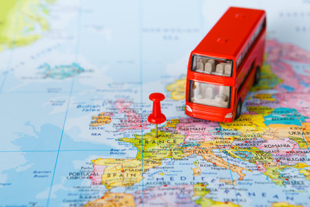 Model Red Bus Sits on Map Pointing to France Among Various European Countries