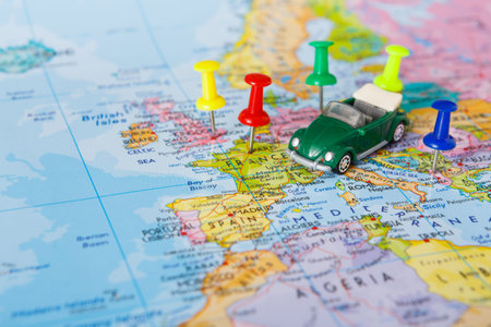 Small Green Toy Car on a Map With Colorful Pins Pointing to Different Locations in Europe