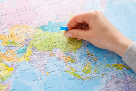 Person Places a Blue Marker on a Map of China in an Indoor Setting in Daytimeの写真素材