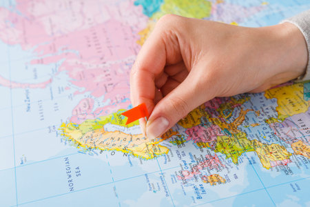 Hand Placing a Marker on a World Map in a Colorful Geography Setting