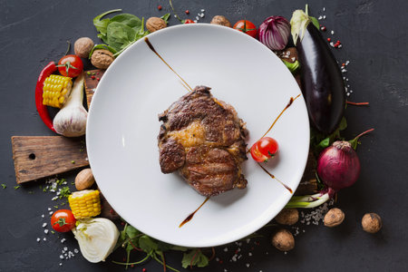Freshly Cooked Steak Served With Colorful Vegetables and Spices on a White Plateの写真素材
