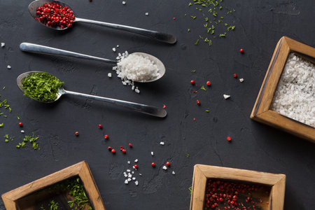 Variety of Spices and Salts Arranged on a Dark Surface With Wooden Containers