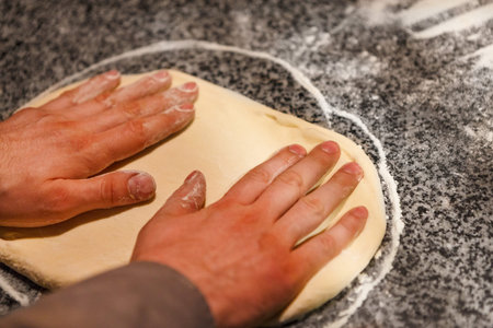 Hands Pressing Dough on a Countertop for Baking Bread in a Kitchen
