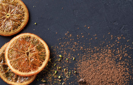 Dried Orange Slices and Cocoa Powder Placed on Dark Surface in Kitchen Setting