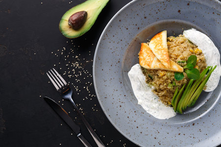 Healthy Quinoa Dish With Avocado Served on a Gray Plate With Cutlery at a Dining Tableの写真素材