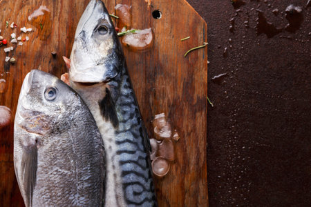 Fresh Fish on Wooden Cutting Board Ready for Cooking in Kitchenの写真素材