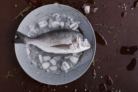 Fresh Fish Placed on Ice With Seasoning on a Plate Before Cookingの写真素材