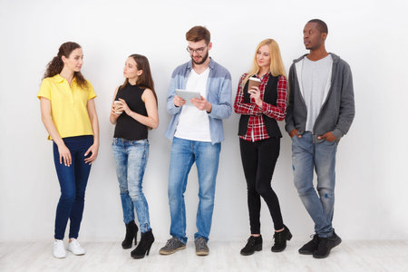 Group of Young People Interacting in a Casual Setting With Technology and Drinksの写真素材