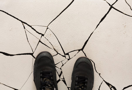 Cracked Surface With Black Sneakers Standing on White Ground During Daylightの写真素材