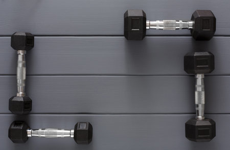 Dumbbells Arranged in a Square Shape on a Gray Wooden Floor Inside a Gym