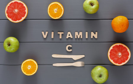 Creative Arrangement of Fruits With Words Showing Vitamin C on Wooden Tableの写真素材
