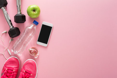 Workout Setup With Weights, Water, Phone, and Snacks on Pink Backgroundの写真素材