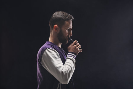 Man Holds Microphone While Having a Serious Moment on Stage With Spotlight