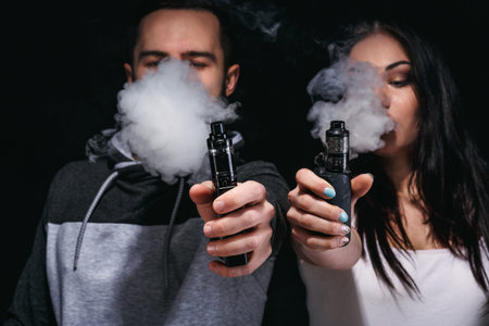 Couple Vaping and Blowing Smoke in a Dark Room During an Indoor Gathering