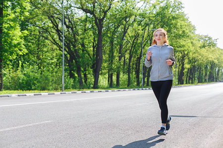 Running on a Tree-Lined Road in Sunny Weather During a Morning Workout Session