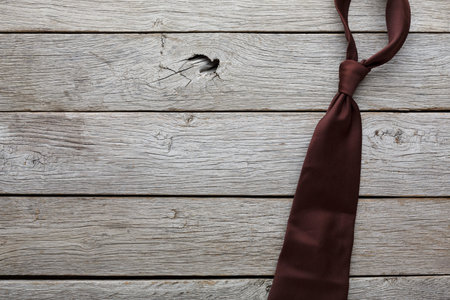 Brown Tie Placed on Wooden Surface for Display or Preparation for an Event in a Formal Settingの写真素材